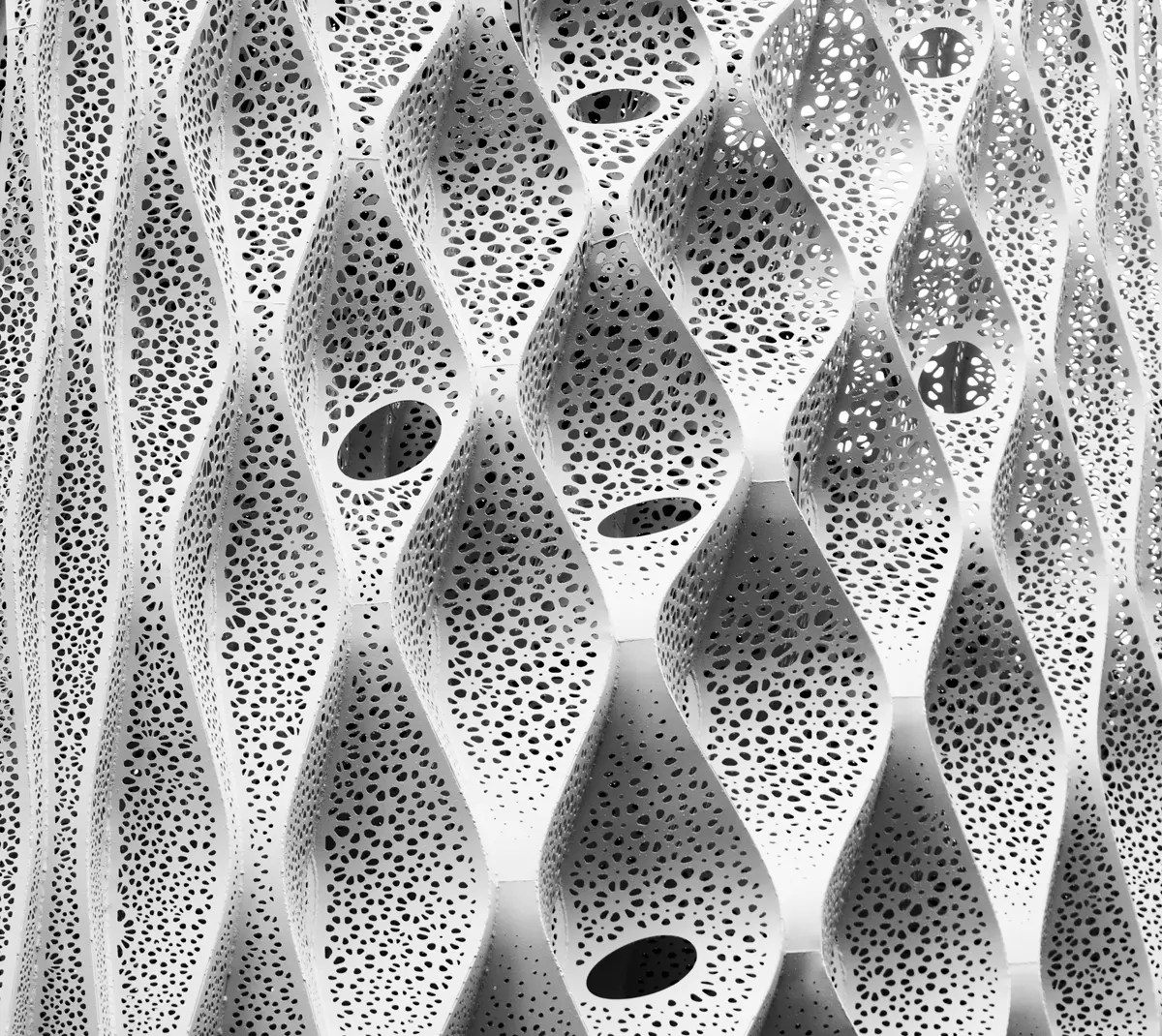 White architectural facade with a wavy, perforated lace-like pattern